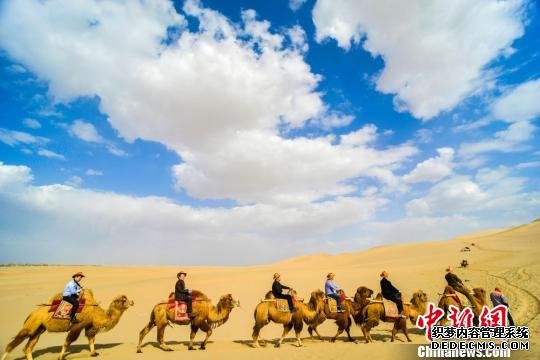 图为游客骑骆驼在鸣沙山观赏大漠风光。　王斌银　摄